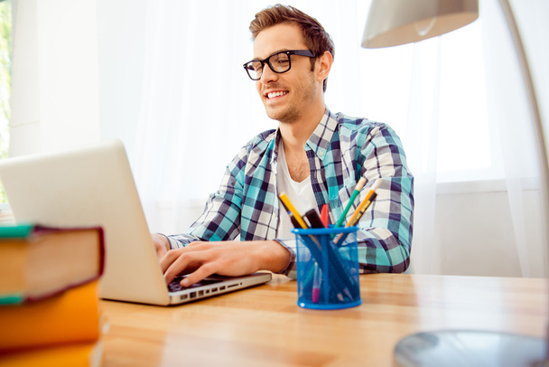 Portrait of young smart businessman in glasses typing on laptop - Foto, afbeelding