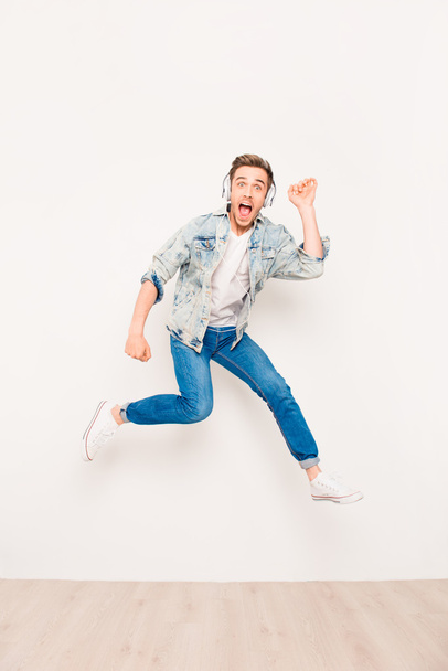 Young energetic crazy man listening music and jumping - Foto, Imagen