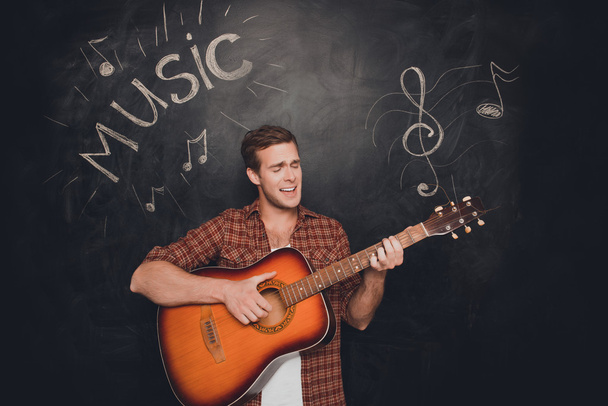 Handsome young instrumentalist playing on the guitar and singer - Photo, image