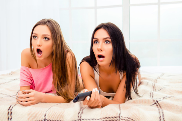 Scared pretty girls watching horror film with popcorn - Фото, изображение