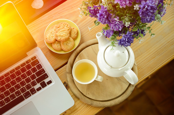 filiżanki, dzbanek do herbaty, ciastka i laptopa na biurko z drewna - Zdjęcie, obraz