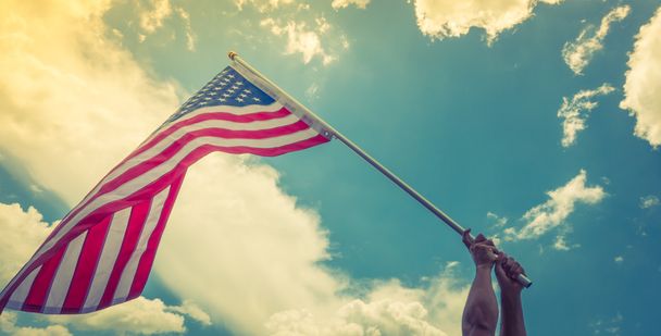 Americká vlajka s hvězdami a pruhy držet rukama proti blu - Fotografie, Obrázek
