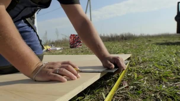 el hombre mide la madera contrachapada en el sitio de construcción
 - Metraje, vídeo