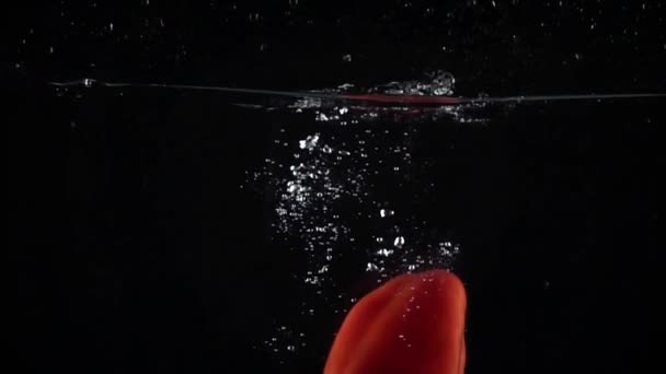 Red ripe bell pepper immersing in water, super slow motion video - Filmagem, Vídeo