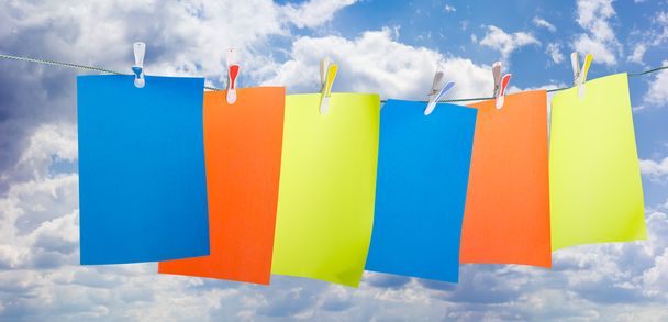 Renkli kağıda tutturmak bir clothespins gökyüzüne karşı - Fotoğraf, Görsel