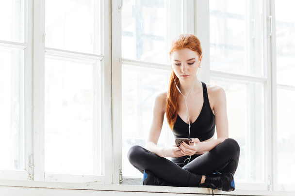 Sportswoman listening to music using smartphone - Zdjęcie, obraz