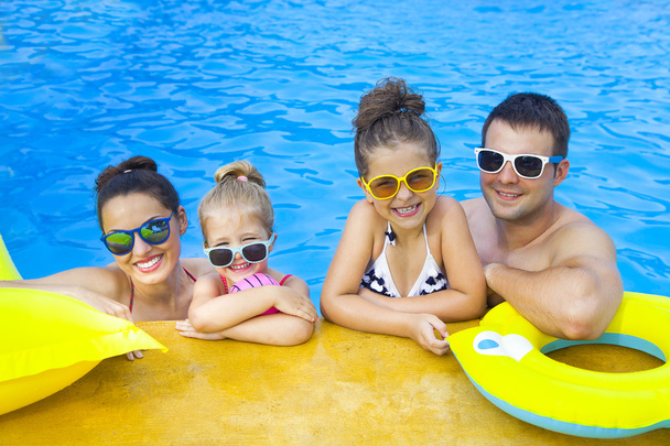 Onnellinen perhe, jossa kaksi lasta pitää hauskaa uima-altaassa
 - Valokuva, kuva