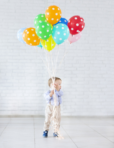 Niño sosteniendo un montón de globos de colores
 - Foto, Imagen