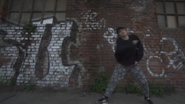 Activa joven hembra bailando en una pared de ladrillo con etiquetas de fondo en cámara lenta
. - Imágenes, Vídeo