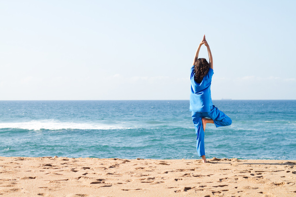 Giovane donna che fa yoga sulla spiaggia - Foto, immagini