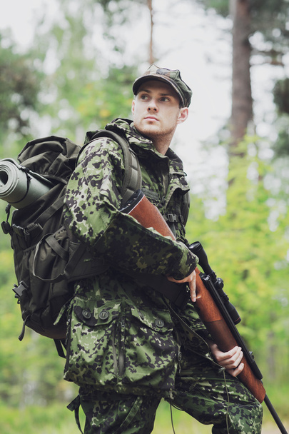 young soldier or hunter with gun in forest - 写真・画像