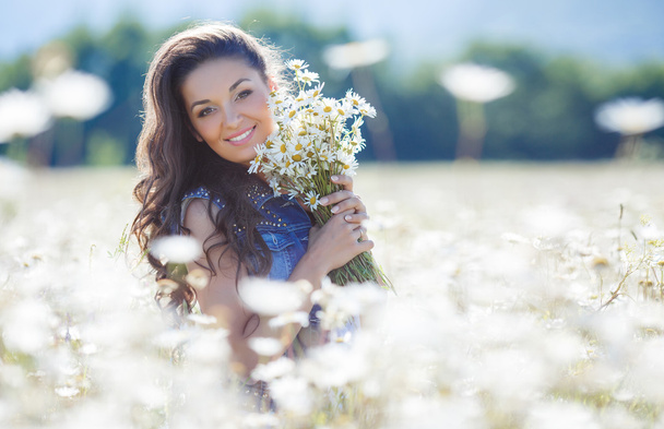 A young woman with a bouquet of white daisies on a meadow - Foto, Imagen