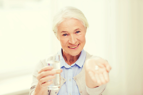 happy senior woman with water and medicine at home - Fotoğraf, Görsel