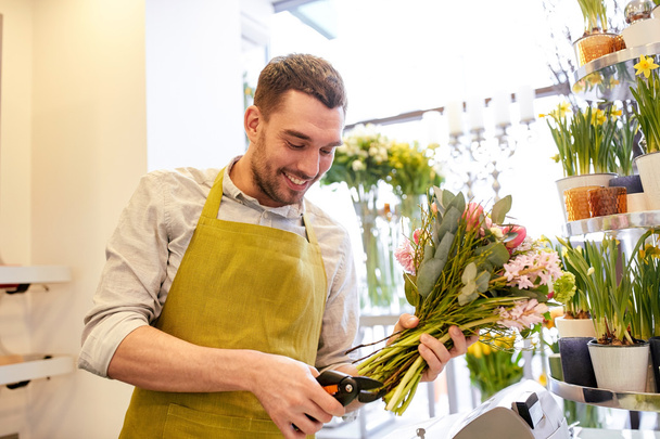 smiling florist man making bunch at flower shop - 写真・画像