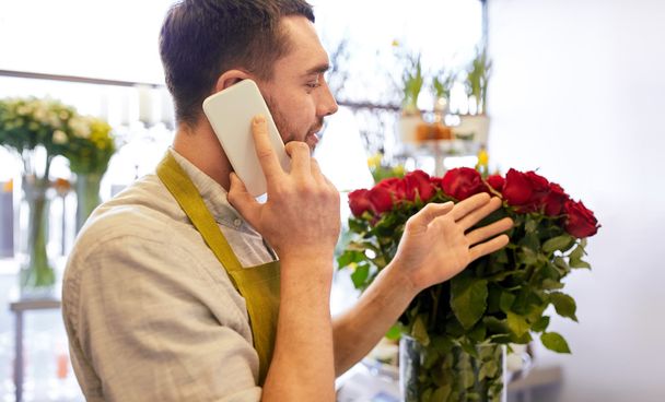 man with smartphone and red roses at flower shop - Foto, imagen