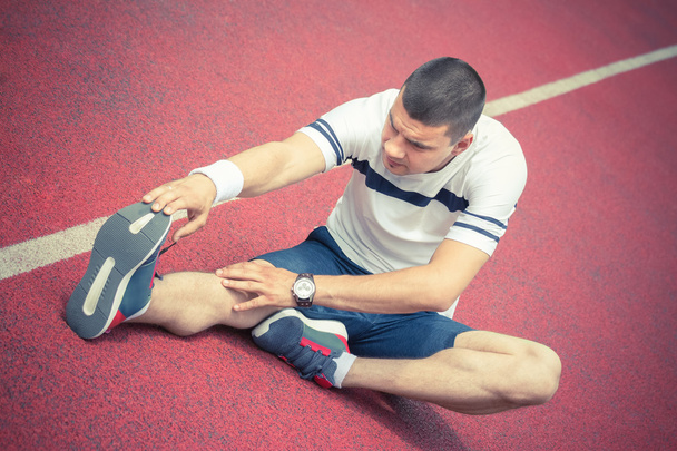 Mann streckt Bein auf der Laufstrecke - Foto, Bild