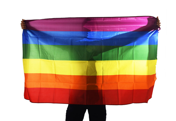 młody gej dumny człowiek rozprzestrzeniania szeroko duże duma flaga homoseksualnych z jego cień za szmatkę - Zdjęcie, obraz