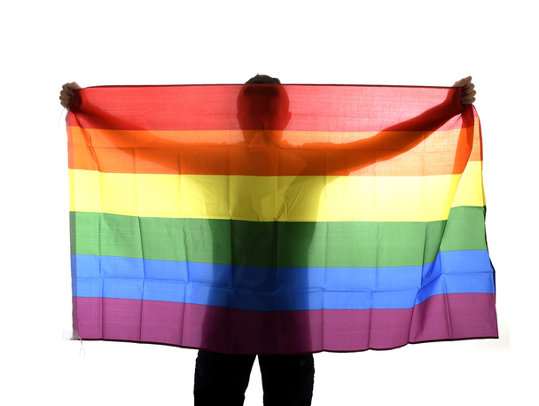 młody gej dumny człowiek rozprzestrzeniania szeroko duże duma flaga homoseksualnych z jego cień za szmatkę - Zdjęcie, obraz