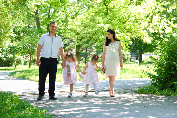gezin met kind en zwangere vrouw lopen in zomer stadspark - Foto, afbeelding