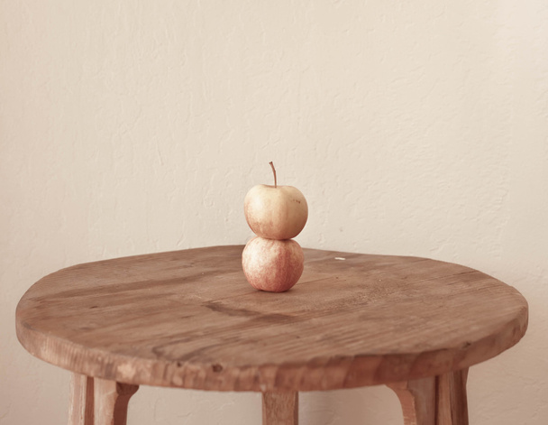 стиглі яблука на дерев'яному столі на білій стіні
  - Фото, зображення