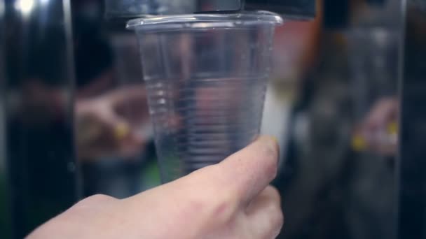 Water flowing into plastic cup. Closeup of hand holding cup with water - Footage, Video