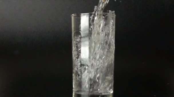 Pouring pure water in glass against dark background. 500 fps slow motion shot - Imágenes, Vídeo