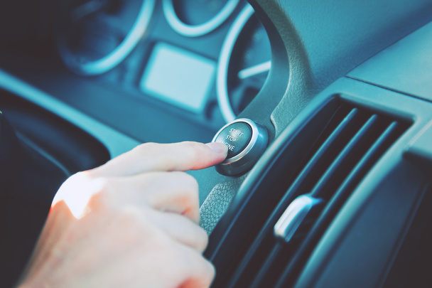 hand pushing a start stop engine button of car - Foto, imagen