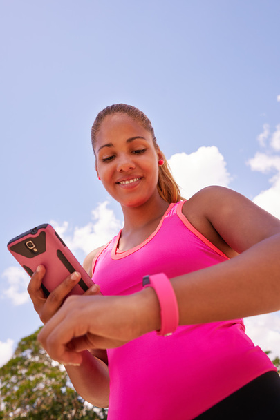 Νεαρή γυναίκα τη σύνδεση Fitwatch ρολόι Fitness με τηλέφωνο - Φωτογραφία, εικόνα