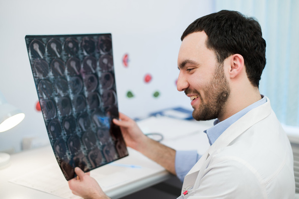 Jeune médecin masculin lisant et examinant un scanner cérébral IRM
 - Photo, image