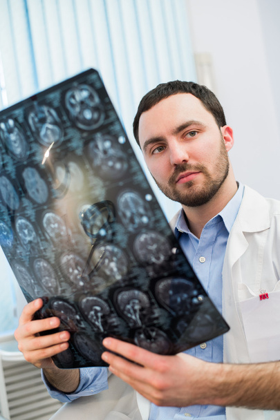 Consultorio médico: retrato del médico masculino de mediana edad que mira la tomografía computarizada
. - Foto, imagen