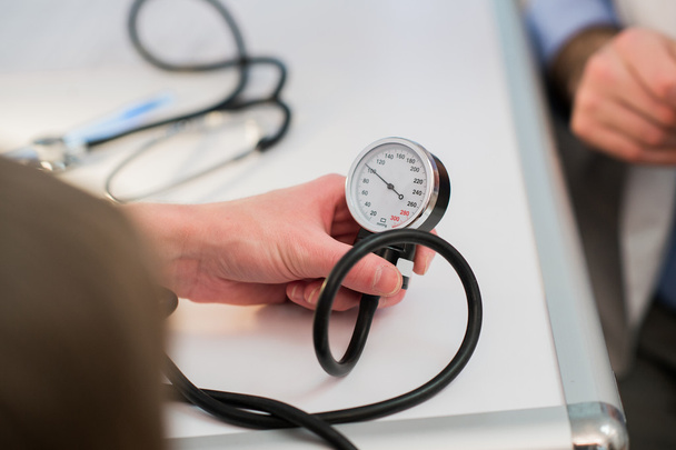 Доктор вимірює кров'яний тиск за допомогою тонометра
 - Фото, зображення