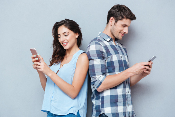 Couple are looking at smartphone over gray background - Fotoğraf, Görsel