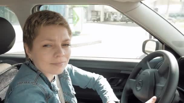 Blond krótkie włosy kobieta jeździ samochód na ulicach miasta - Materiał filmowy, wideo