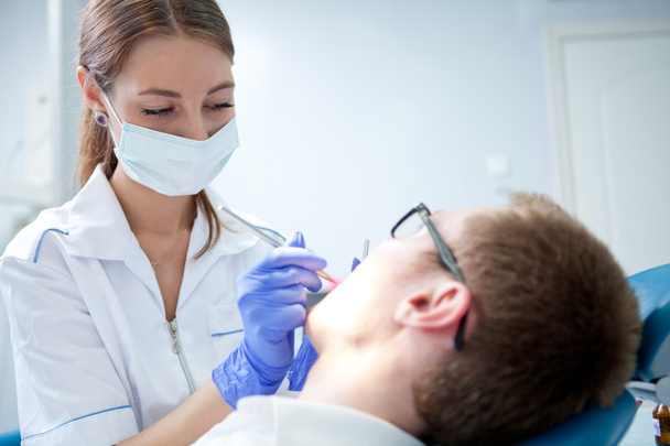 Dentist at work on woman patient in office - 写真・画像
