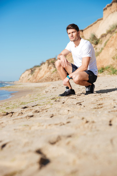 Sportsman sitting alone on the beach - Фото, зображення