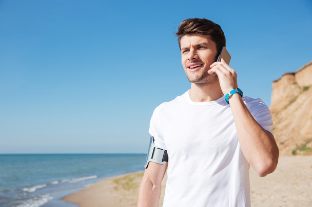 Sportsman talking on mobile phone at the beach - Photo, Image