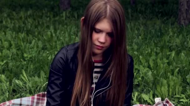 Csinos, fiatal lány hallgat zenét a fejhallgatót a parkban - Felvétel, videó