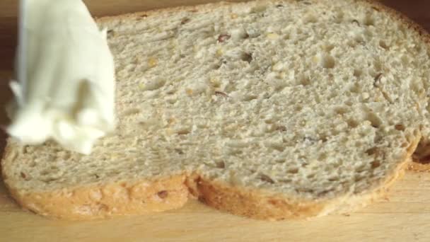 Close up video: spreading creamy butter on a piece of bread - Felvétel, videó