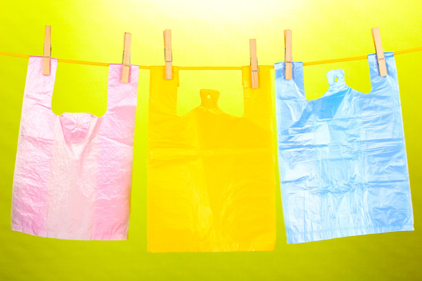 Cellophane bags hanging on rope on green background - Foto, imagen