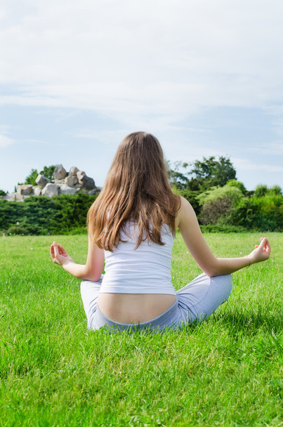 Nainen meditoi vihreällä nurmikolla puistossa
 - Valokuva, kuva