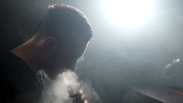 young vaper man exhaling big clouds of smoke with e-cigarette vape in slowmotion - Footage, Video
