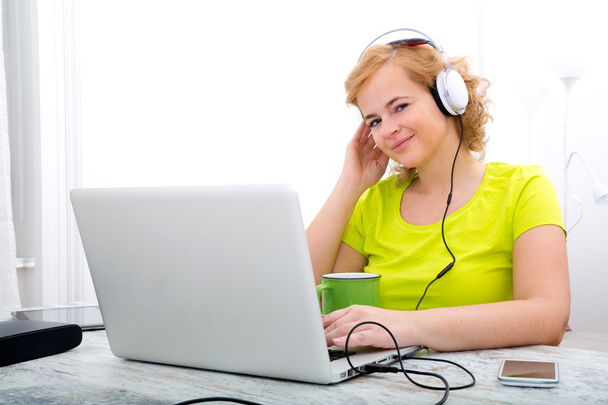 Young plus size woman listening to Audio while working on a lapt - Φωτογραφία, εικόνα