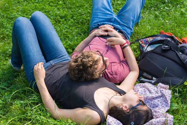 Mladý dospělý pár vleže na svěží zelené trávě v parku, relaxační, všeobjímající. Skuteční lidé, přírodní barvy. Conpept šťastný vztah a džungle. - Fotografie, Obrázek