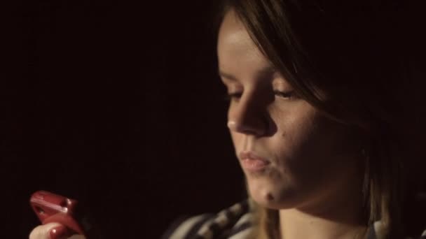 beautiful woman looking at smartphone in dark room - Záběry, video