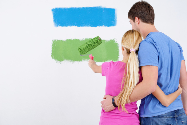 Happy couple paint wall at new home - Фото, зображення