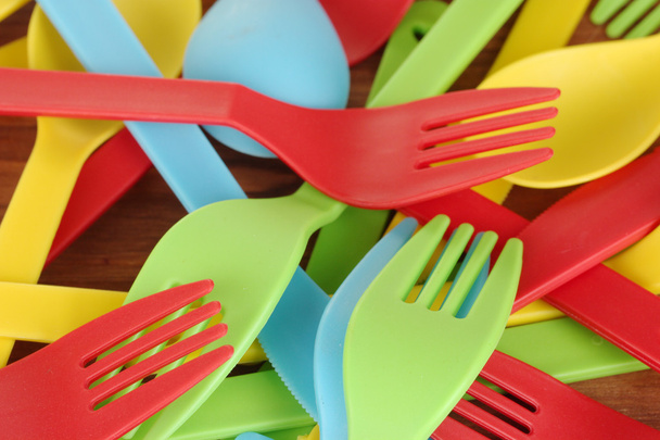 Bright plastic disposable tableware on wooden background close-up - Fotoğraf, Görsel
