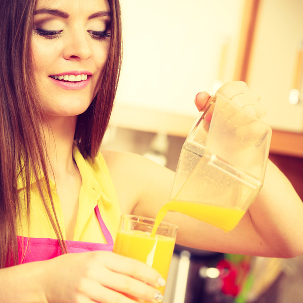 Woman make orange juice in juicer machine pouring drink in glass  - Φωτογραφία, εικόνα