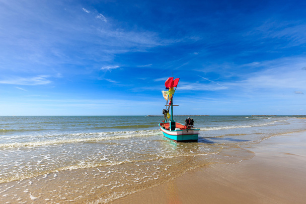 Petit bateau de pêche sur la plage avec ciel bleu
 - Photo, image