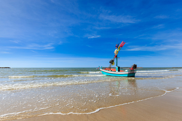 Petit bateau de pêche sur la plage avec ciel bleu
 - Photo, image