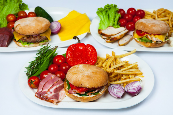 Burger frais dans une assiette avec légumes et frites. Grand hamburger. Ingrédients pour hamburgers. Vue du dessus
 - Photo, image